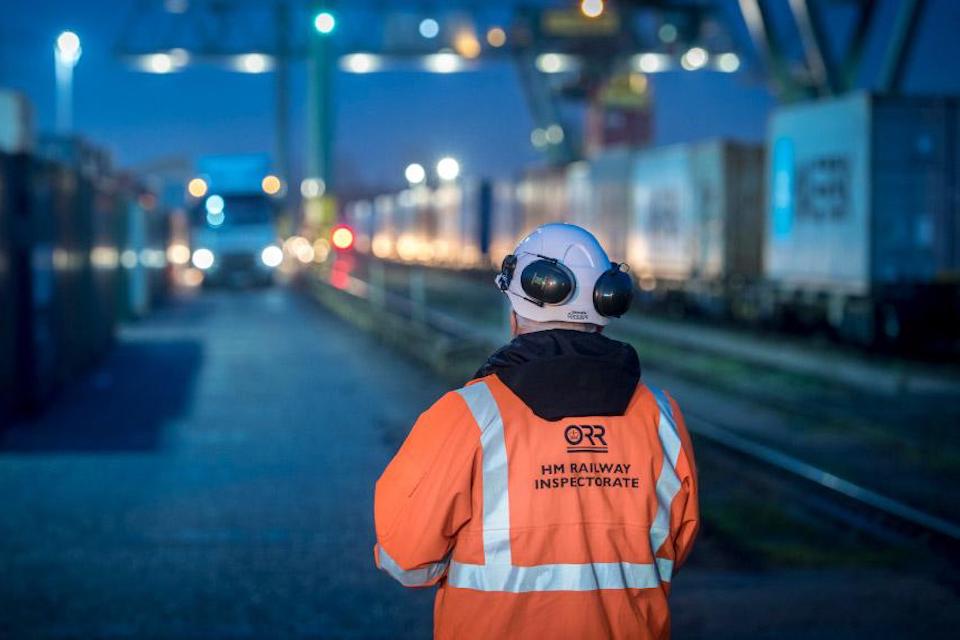 Railway inspector with back to camera looks out over freight terminal