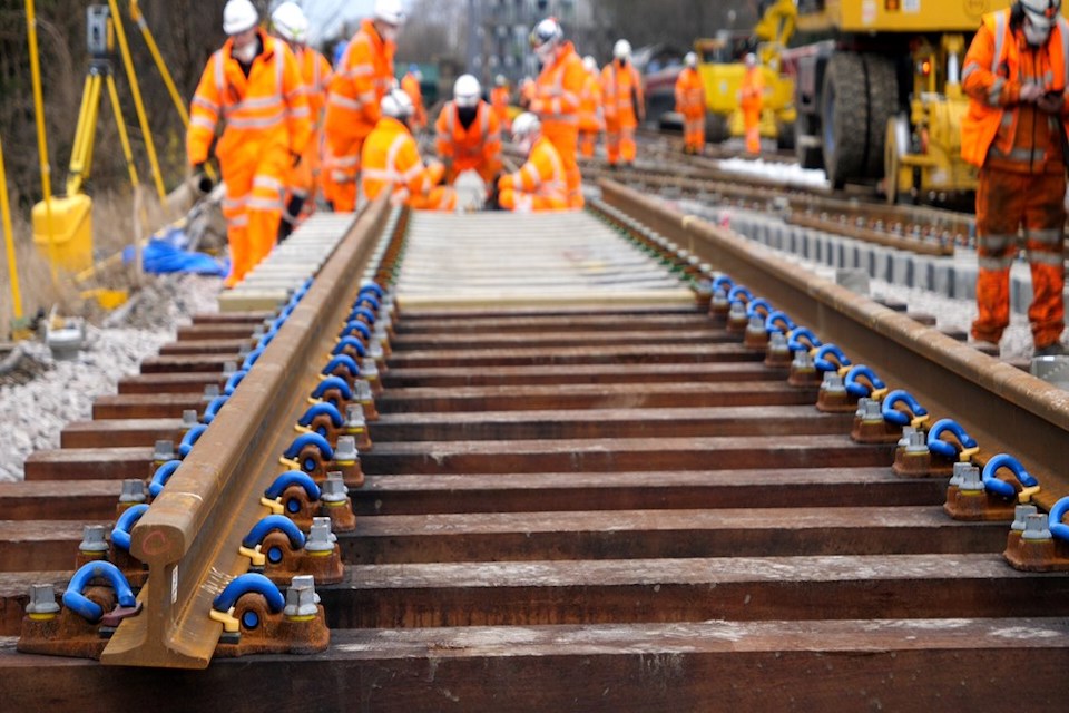 Rails in foreground with orange suited engineers in background