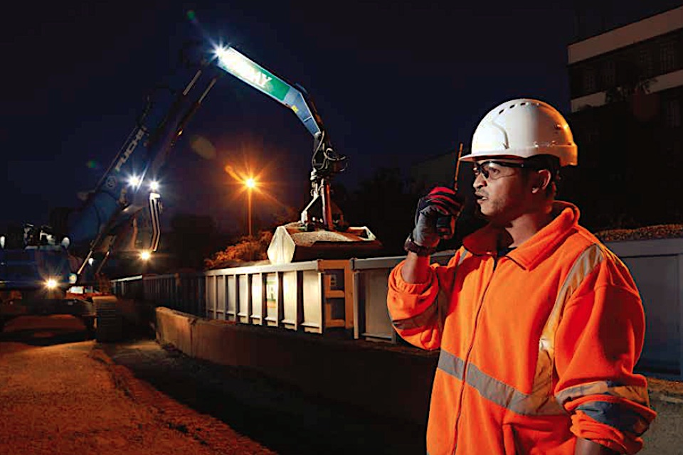 Nighttime shot of a supervisor on a walkie talkie directing an aggregates train into a terminal